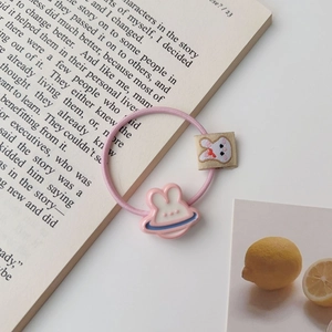 Détail d'un élastique à cheveux rose avec breloque lapin 3D sur une page de livre