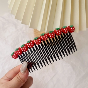 Détail du peigne à cheveux pour enfant avec dix ornements de fraises sur base noire