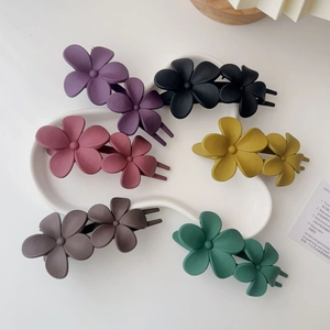 Détail de pinces à cheveux fleur mat en six couleurs sur plateau blanc pour coiffures d'été