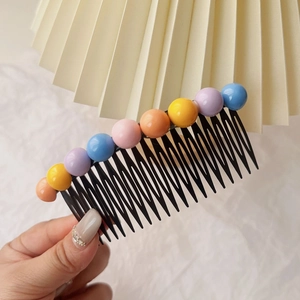 Détail d'un peigne à cheveux noir avec neuf perles colorées pour coiffures de filles