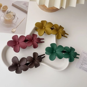 Détail de quatre pinces à cheveux fleurs mates en jaune, bordeaux, vert et marron foncé
