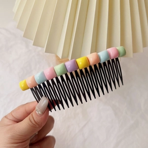 Détail d'un peigne à cheveux pour fille avec perles macaron colorées pour coiffure