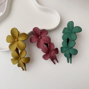 Détail de trois pinces à cheveux fleur mate aux tons jaune, rose et vert pastel