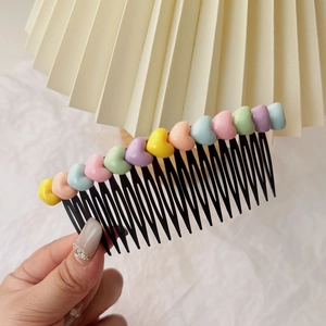Gros plan d'un peigne à cheveux pour enfants avec des cœurs colorés façon macaron