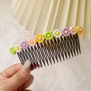 Détail de peigne à cheveux enfant avec dix fleurs de marguerite colorées en résine