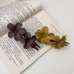 Détail de pinces à cheveux à fleurs mates marron et jaune moutarde sur livre