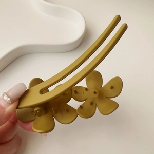 Gros plan détaillé d'une grande pince à cheveux mate jaune moutarde avec motif floral