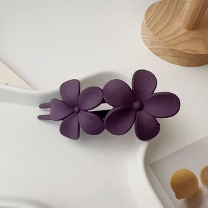 Détail de la pince à cheveux fleurs violettes mates sur un plateau en céramique