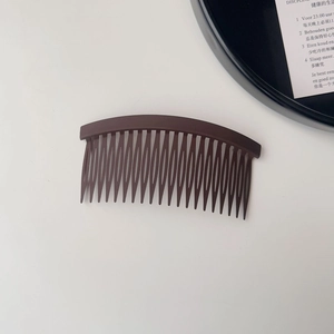 Detail view of dark brown matte hair comb with dense teeth for fixing loose hair