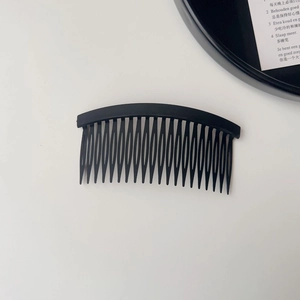 Detail view of a black 22-teeth hair side comb with a matte finish and curved design