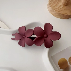 Gros plan d'une pince à cheveux double fleur rouge vin mat sur plateau blanc