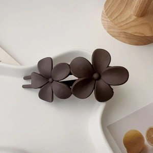 Détail de la double pince à cheveux fleur marron mat sur un plateau en céramique