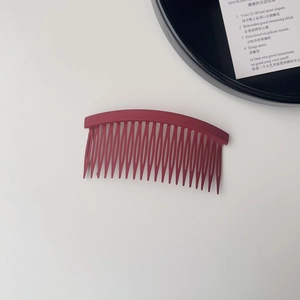 Close-up of matte burgundy hair comb for hairstyling on clean white background