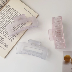 Three large matte hair claws in lavender, blue, and pink colors on a white desk