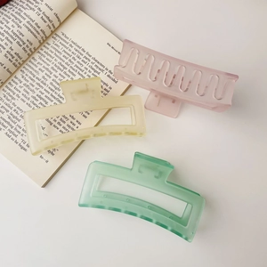 Trois grandes pinces à cheveux mates rose, beige et vert menthe sur un livre