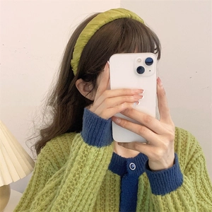 Detail of light green pleated headband with silk texture worn by a model in soft lighting