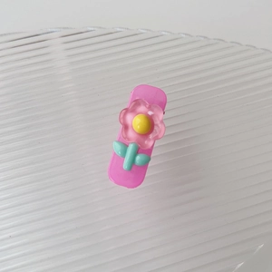 Dettaglio macro del fermaglio per capelli rosa con fiore in resina su vassoio bianco