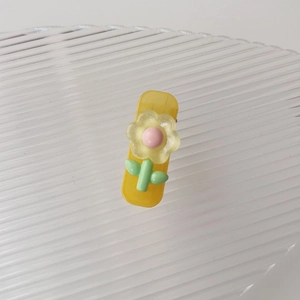 Dettaglio di un fermaglio giallo in resina con fiori 3D e accenti rosa pastello