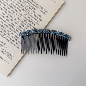 Detail of multi-tooth hair comb with blue and silver rhinestones on a vintage book