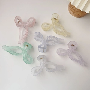 Flat lay of six large jelly-colored bow hair claws in matte pastel finishes on white background