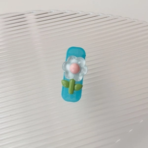 Dettaglio molletta per capelli in resina a fiore con base blu e petali bianchi