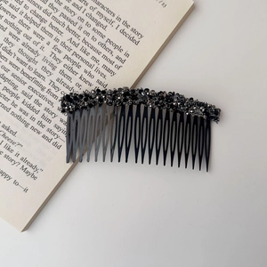 Close-up of a black hair comb with glittering rhinestones on a decorative book background