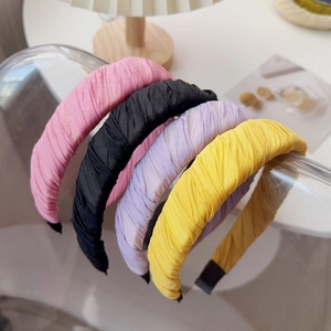 Close-up of four pleated fabric headbands in pink, purple, yellow, and black colors
