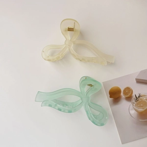 Detail view of matte bow hair claws in cream yellow and mint green for summer styling