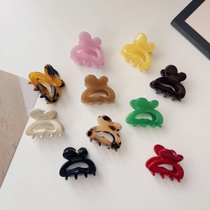 Close-up of ten colorful resin mini hair claws with heart shapes and French text engraving