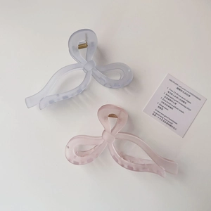 Detail view of large bow hair claws in matte translucent blue and pink with leopard print