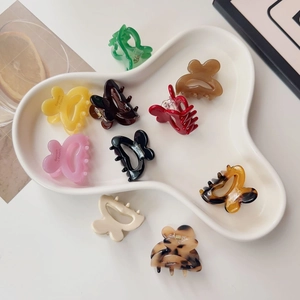 Chic butterfly mini hair claws in various colors displayed on a white ceramic tray