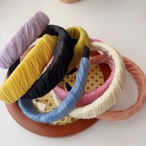 Detail view of colorful ruched fabric headbands stacked on a rustic woven tray