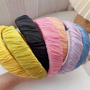 Detailed view of six colorful pleated fabric headbands held together in various bright tones