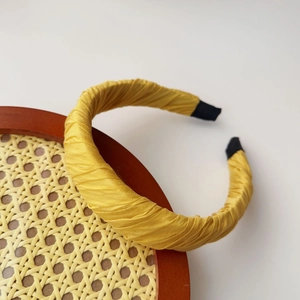 Detail view of bright yellow pleated fabric headband on a rustic rattan tray