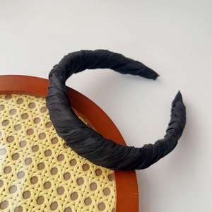 Detail of a black twisted fabric headband on a rustic rattan tray for styling