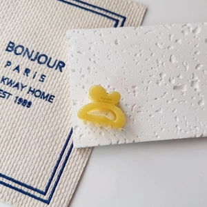 Detailed top view of a small yellow French style barrette clip on a white textured stone surface