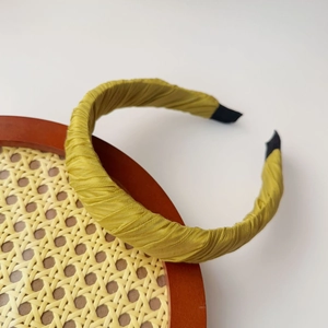 Detail of a bright yellow fabric headband with spiral texture on a wooden tray