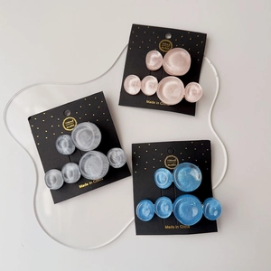 Detailed view of handmade resin circle hair clips in pink and blue on black cards