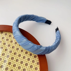 Detailed close-up of blue knotted headband with elegant pleated satin fabric texture