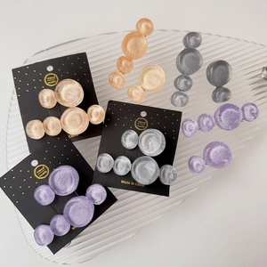 Detail of round marble resin hair clips in champagne and purple on a glass plate