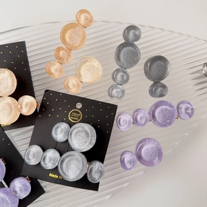 Detail of marble pattern resin hair clips on a striped glass tray in soft lighting