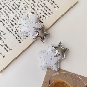 Close-up of Y2K star hair clips with silver sequins and heart patterns on book background