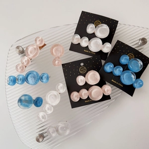 Close-up of pastel resin marble hair clips with pearl texture on a glass display tray