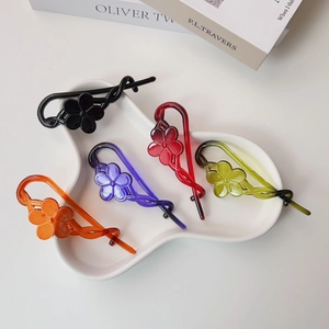 Detailed view of colorful resin flower banana hair clips on a white ceramic tray