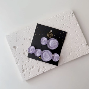Detail of purple resin round hair clips with pearlescent texture on premium card
