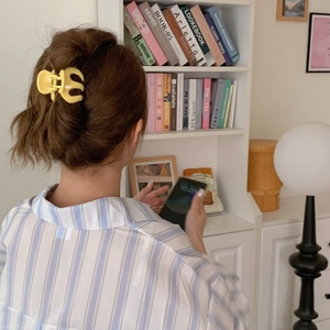 Rear view of a yellow pumpkin hair claw clip securing a ponytail on brown hair