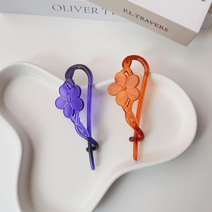 Detailed view of floral resin banana clips in purple and orange on a ceramic tray