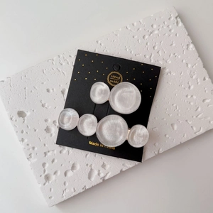 Detail of two iridescent resin hair clips on a decorative card, showing pearly texture