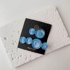 Close-up of blue resin wavy round hair clips with pearl luster on a display card
