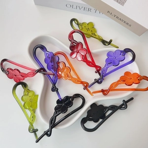 Close-up of colorful translucent resin flower banana clips in a minimalist ceramic tray